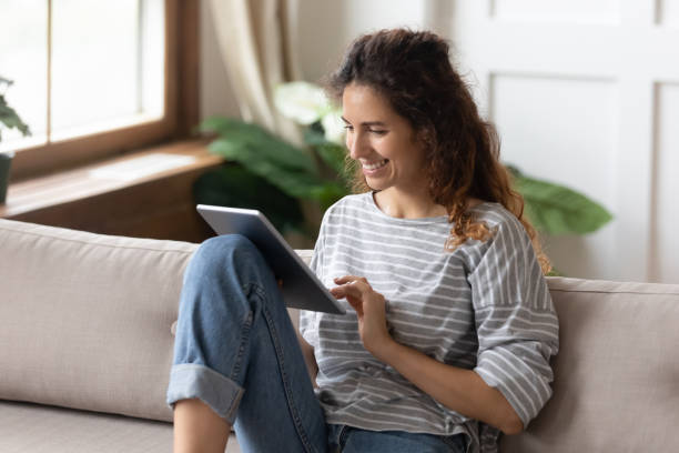 istock Woman sitting on sofa using tablet device buying on internet 1270939956