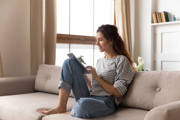 istock Woman sitting on couch use tablet device chat with friend 1270939957