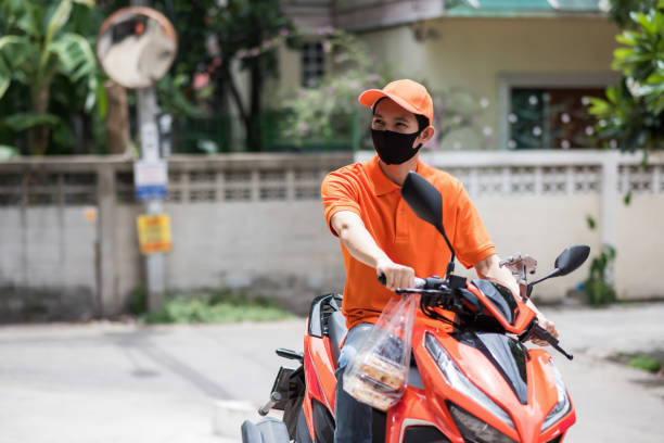 istock deliveryman with face mask on bike wait for customer 1270940020