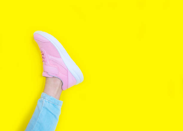 istock pink sneakers and blue jeans on a yellow background. Mockup. Copy space 1270944619