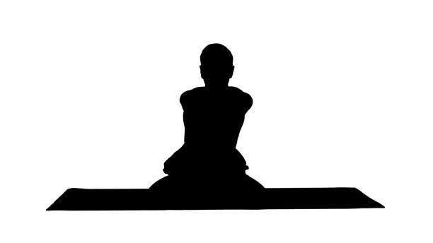 silhouette sporty beau jeune homme pratiquant le yoga, assis les jambes croisées dans adho mukha padmasana, se penchant vers l’avant dans la variation de lotus pose - men yoga meditating cross legged photos et images de collection