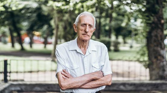 Close up portrait of senior adult man with gray hair outdoors in the city park