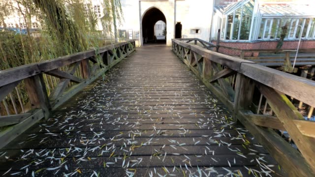 Walk across the wooden bridge to the entrance in the historical building, POV