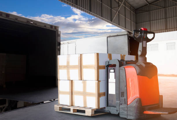 istock Electric forklift pallet jack with stack of carton boxes on pallet loading into container truck. Shipment, Cargo freight, Delivery distribution warehouse. Logistics and transportation. 1270953128