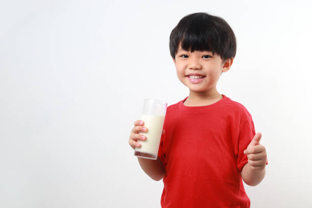 Portrait Of Happy Girls Sitting Holding Glasses With Milk At Table