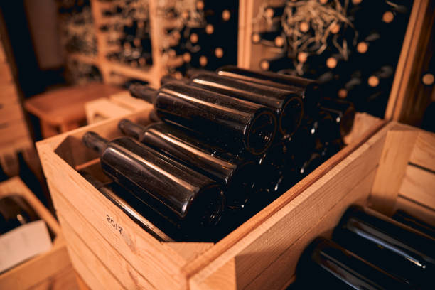 bouteilles poussiéreuses de vin dans la salle de stockage ou la cave à vin - dust old cabernet sauvignon grape aging process photos et images de collection