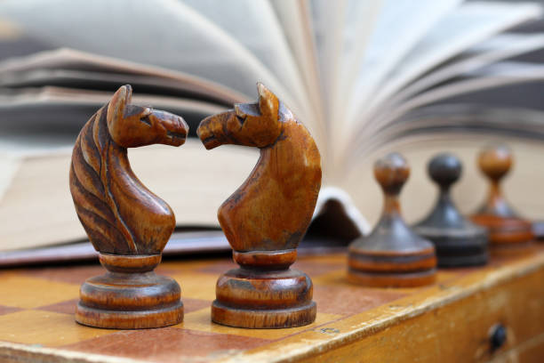 istock Two wooden horses chess and a book background 1270962984