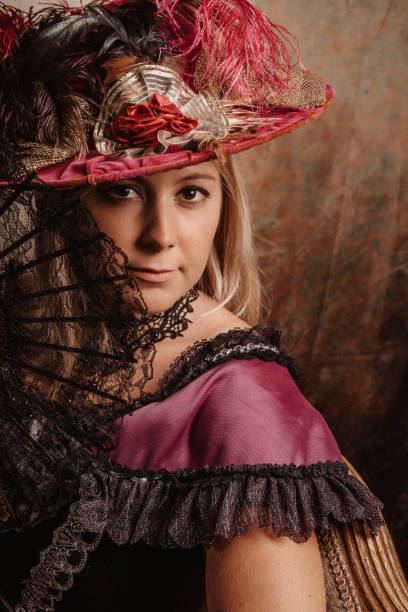 istock Blond model in historical victorian dress with hand fan looking at camera 1270963452