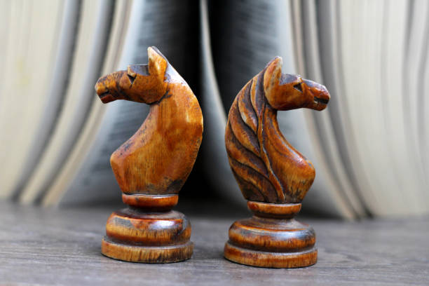 Side view of one messy painted smudged cream off white colored chess piece horse or knight over dark gray black rough rustic scratched background. Conceptual photograph of  power alone on road. No text. No people. Copy space