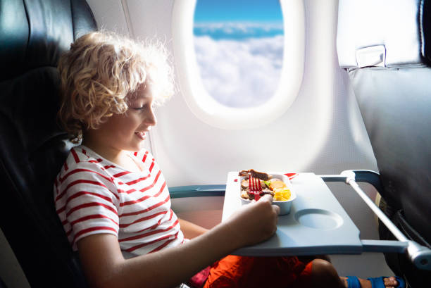 Child in airplane. Kids fly. Children flight meal Child in airplane window seat. Kids flight meal. Children fly. Special inflight menu, food and drink for baby and kid. Boy eating healthy lunch in airplane. Travel and family vacation. airplane food stock pictures, royalty-free photos & images