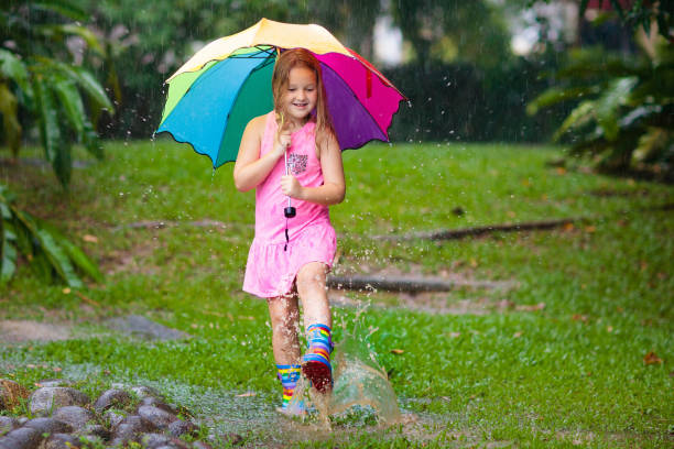 istock Kid with umbrella playing in summer rain. 1270971527