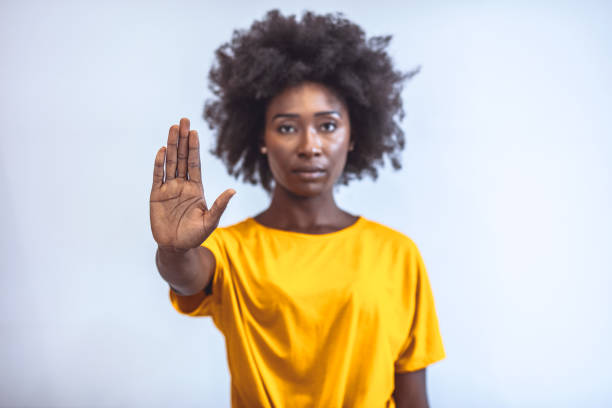 Stop and think... Photo of African american young woman making stop gesture with palm of her hand on grey background stop stock pictures, royalty-free photos & images
