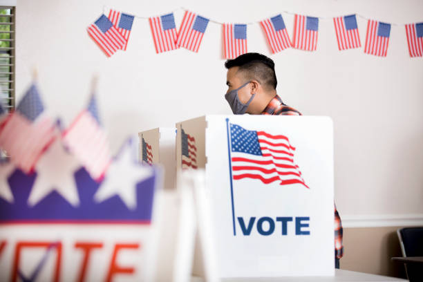 Voters placing their ballots.  Wearing face masks. Voters wear protective face masks.  Asian voter at the ballot box casting his vote. democratic party usa photos stock pictures, royalty-free photos & images