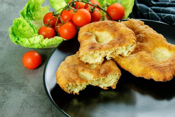 istock Sliced and whole navajo flatbread with tomatoes cherry and lettuce on the black dish. 1270977471