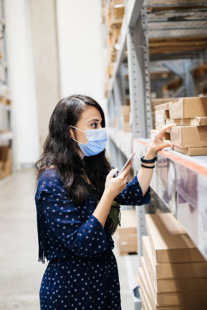 istock Woman with protective mask using smart phone  and choosing product at store 1270986780