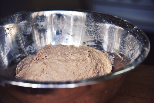 A close up of a stainless steel bowl. Handmade bread dough rising in a stainless steel bowl. High quality photo.