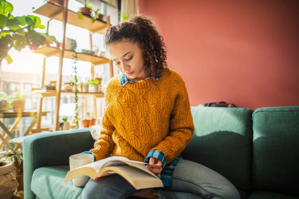 istock Young woman reading a book at home 1270988380