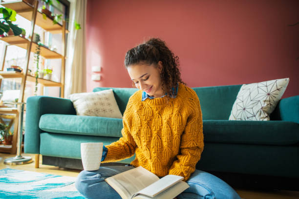 istock Young woman reading a book at home 1270988383