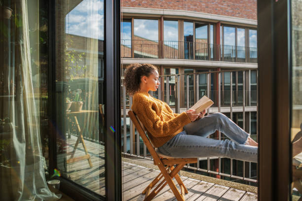 young woman reading a book at home - reading outside imagens e fotografias de stock