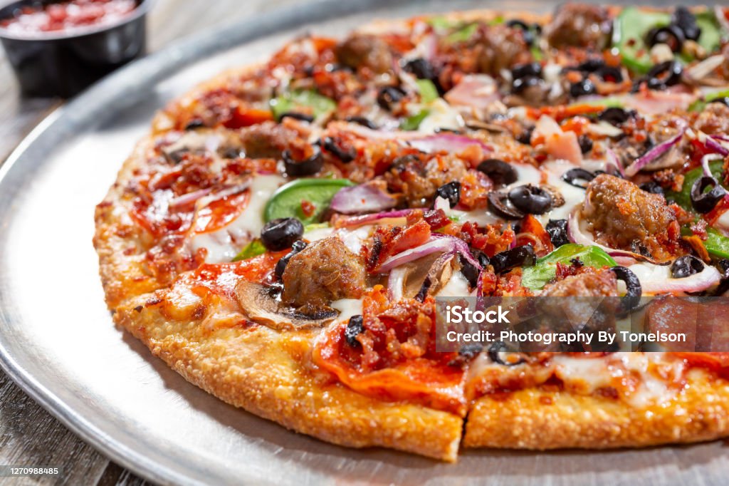 supreme pizza A view of a meat and veggie pizza pie, in a restaurant or kitchen setting. Pizza Stock Photo