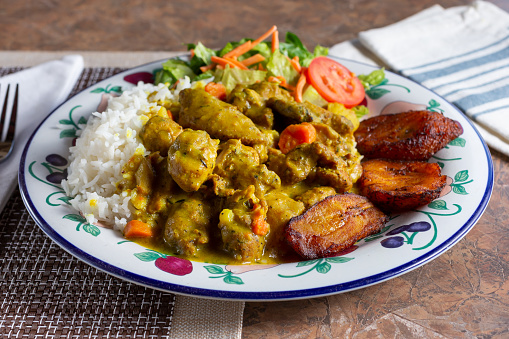 A view of a plate of curry chicken in a restaurant or kitchen setting.