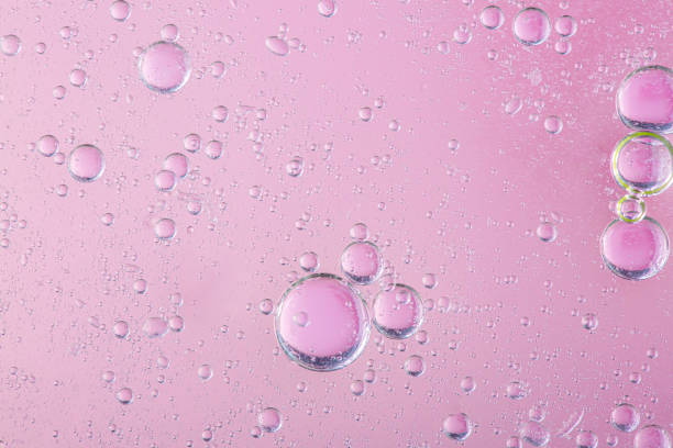 oil with bubbles on coral background. pink abstract space background. soft selective focus. macro of oil drops on water surface. copy space. air bubbles in water - wet strawberry macro fruit imagens e fotografias de stock