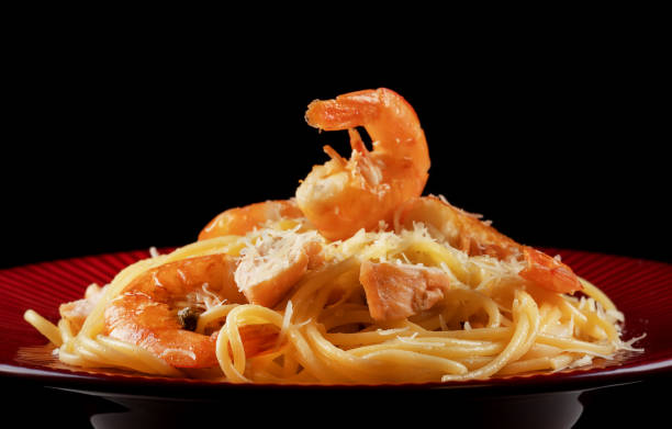 istock Spaghetti with shrimps and salmon on red plate. 1270993927