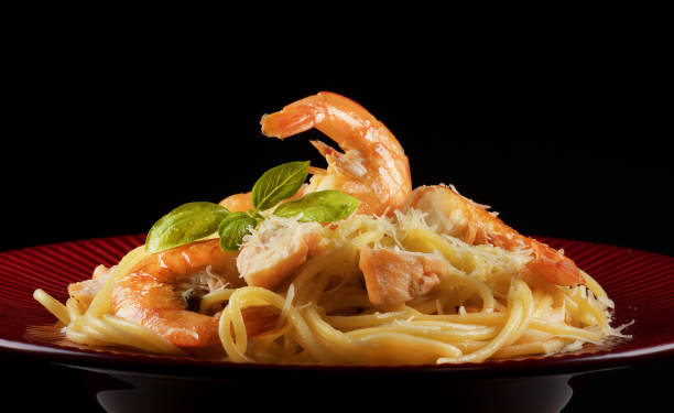istock Spaghetti with shrimps and salmon on red plate. 1270993936
