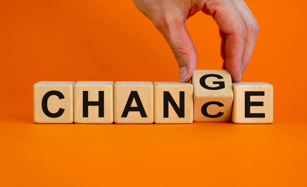 Hand flips a cube and changes the word 'change' to 'chance'. Beautiful orange background, copy space. Business concept.