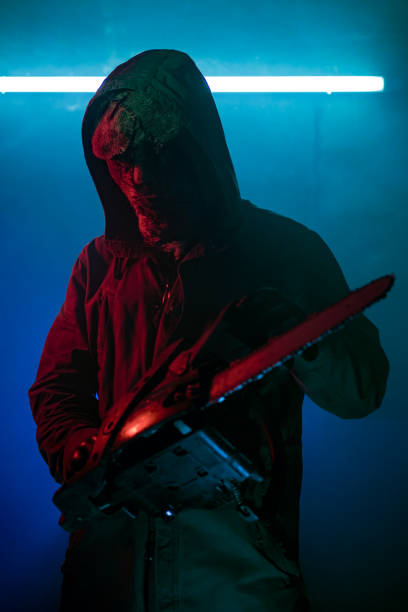 istock Spooky man with a chainsaw standing in the dark 1271000776