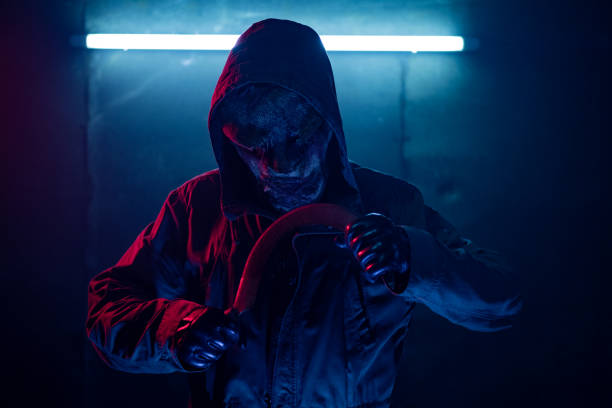istock Horrific man in mask with a weapon waiting in dark 1271004116