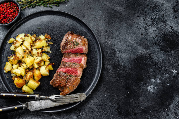 bistecca alla griglia con patate, carne di manzo. sfondo nero. vista dall'alto. spazio di copia - steak strip steak prepared potato grilled foto e immagini stock