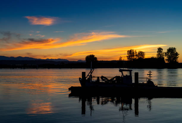 Sunset Over Jetty Island Boat in Silhouette in foreground Sunset Over Jetty Island Boat in Silhouette in foreground everett washington state stock pictures, royalty-free photos & images