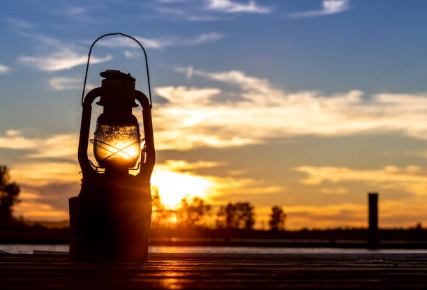Vintage Railroad Lantern Lights Up in foreground of sunset on water Vintage Railroad Lantern Lights Up in foreground of sunset on water everett washington state stock pictures, royalty-free photos & images