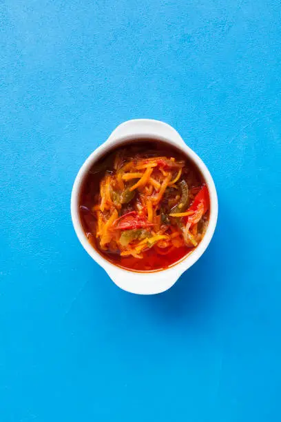 Vegetable stew in a spicy tomato sauce. Blue background, copy space, top view.
