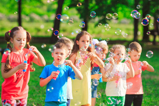istock Group of children blowing soap bubbles in a garden 1271010622