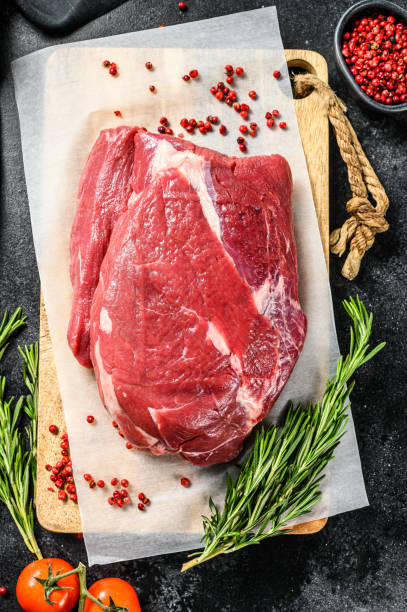 istock Raw brisket beef cut on a wooden cutting board. Black Angus beef. Black background. Top view 1271010665