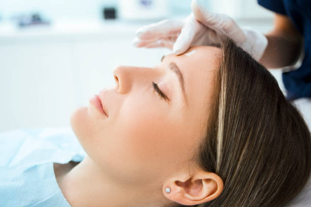 美容顔の治療のための患者の顔を準備する美容師 - exfoliating scrub ストックフォトと画像