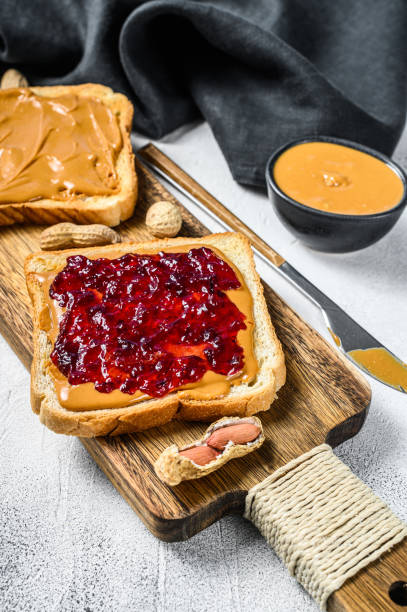 istock Peanut butter and jelly on white bread toasts.  White background. Top view 1271016711