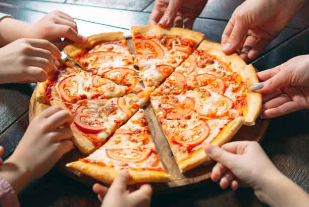 istock Hands taking pizza slices from wooden table, close up view. 1271021591
