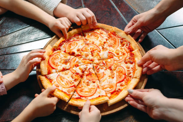 istock Hands taking pizza slices from wooden table, close up view. 1271021659
