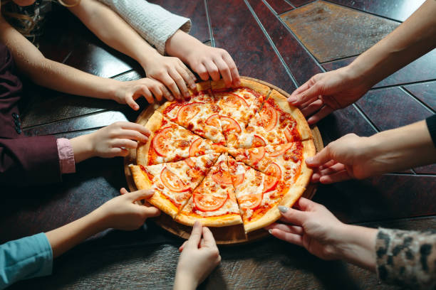 istock Hands taking pizza slices from wooden table, close up view. 1271021670