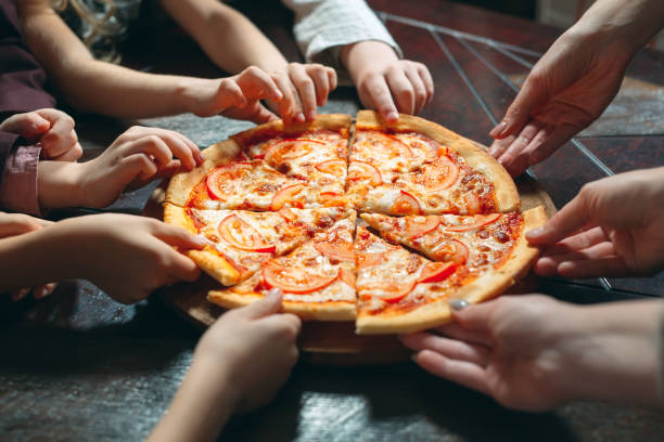 istock Hands taking pizza slices from wooden table, close up view. 1271021741