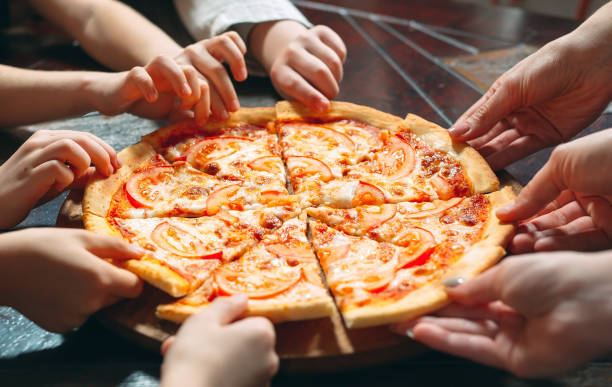 istock Hands taking pizza slices from wooden table, close up view. 1271021744