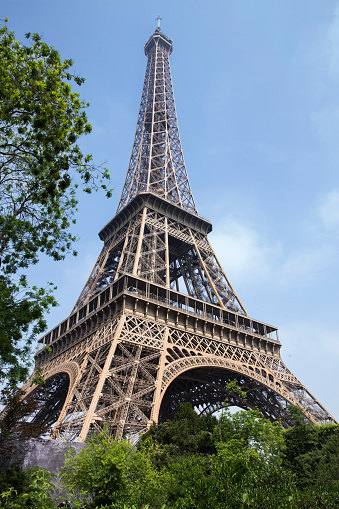 Eiffel Tower against the backdrop of the Champe de Mars park, city-line and blue sky