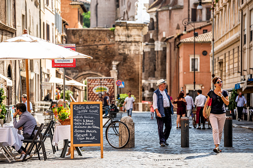 Rome, Italy - September 4, 2018: Historic city on summer day and many people tourists sightseeing by restaurant cafe on Via del Portico d'Ottavia