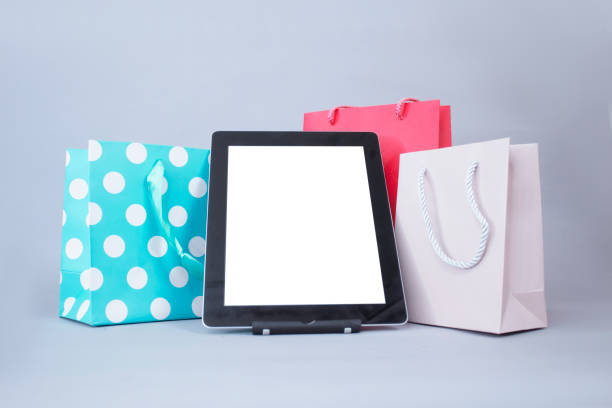 online shopping concept. close-up tablet mockup with white screen with bright gift bags on gray background. - ipad shopping gift retail imagens e fotografias de stock