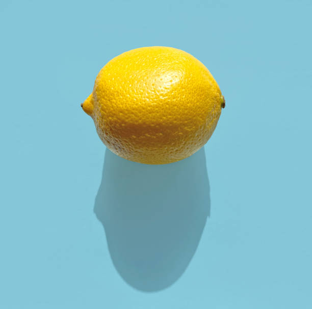 istock fresh lemon with long shadow on blue background, top view 1271028442