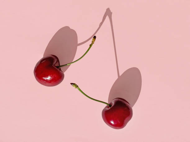 istock fresh sweet cherries with long shadows isolated on pink background, top view 1271030862
