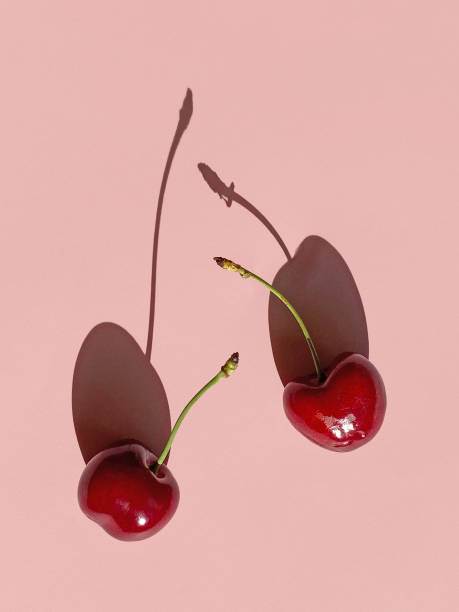 istock fresh sweet cherries with long shadows isolated on pink background, top view 1271030867